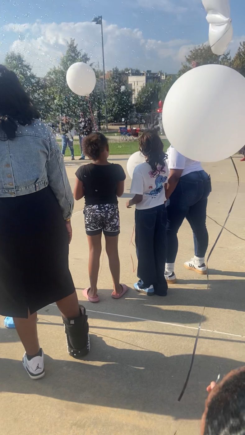 Children and families holding white balloons before the release