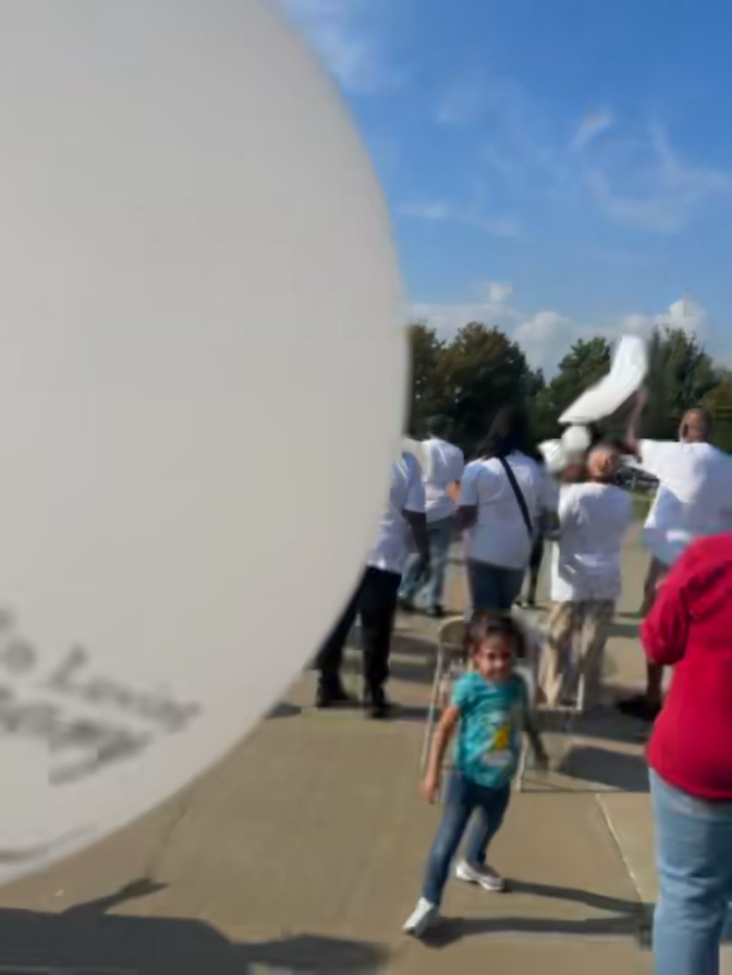A child at the balloon release holding a white balloon