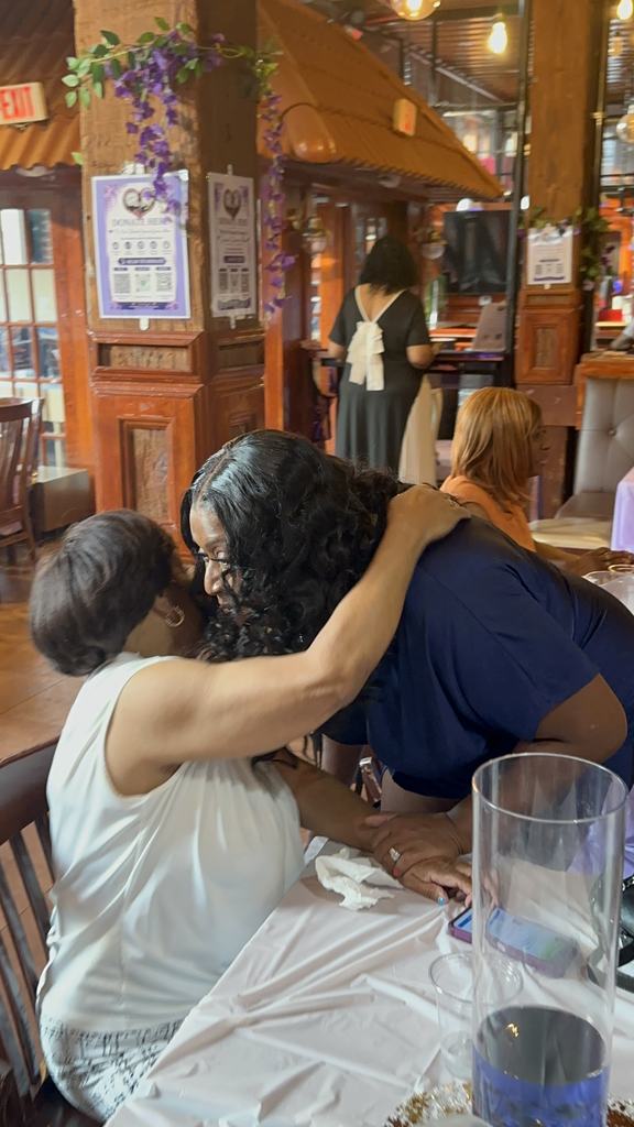 The founder embracing a guest at her table