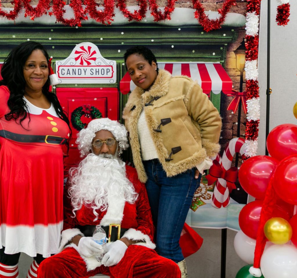 Volunteers with Santa at the Candy Shop photo backdrop