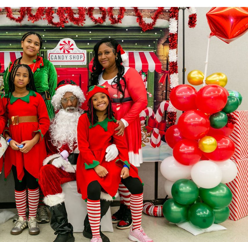 A child with Santa at the Mending Minds and Hearts toy drive Candy Shop backdrop